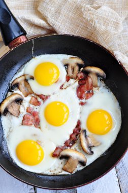 Bir domuz pastırması ve mantarlı ahşap bir masa üzerinde kızarmış yumurta kahvaltı