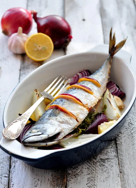 Fresh mackerel fish baked with a lemon, bow, salt and pepper on a wooden table — Stock Photo, Image