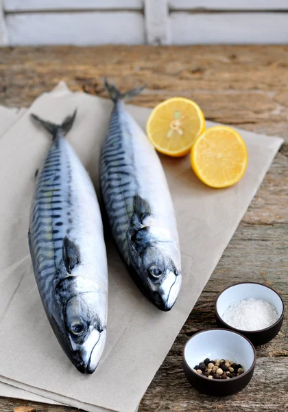 Fresh mackerel fish with a lemon, bow, salt and pepper on a wooden table — Stock Photo, Image