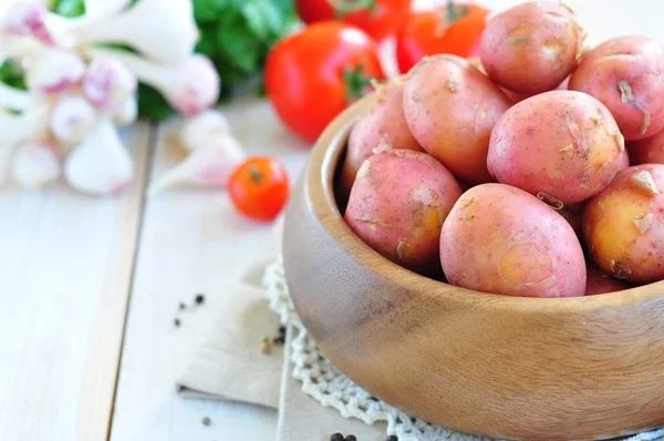 Houten plaat met verse aardappelen op witte achtergrond — Stockfoto