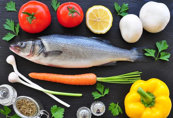 Roher Fisch mit frischem Gemüse auf schwarzem Hintergrund — Stockfoto