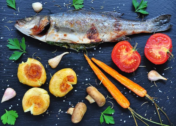 Baked fish with vegetables on a black background — Stock Photo, Image