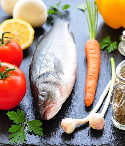 Raw fish with fre Raw fish with fresh vegetables on a black background Stock Photo