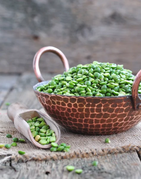 Dried green split peas in a copper plate on a wooden table — Stock Image Dried green split peas in a copper plate on a wooden table Royalty Free Stock Images