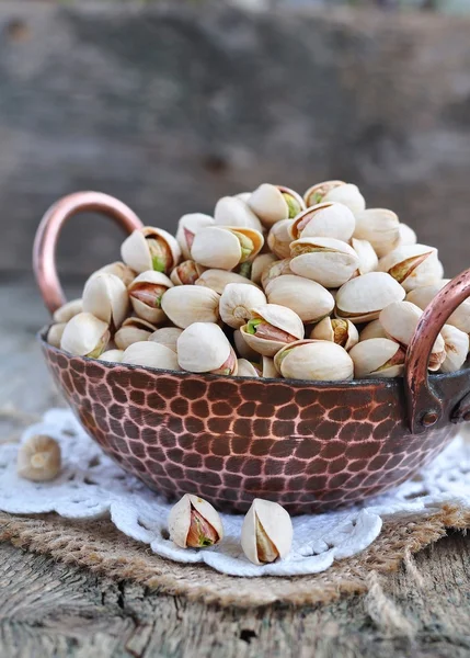 Pistachio  in a copper plate on a wooden table — Stock Photo, Image