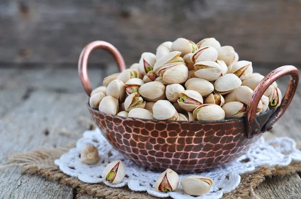 Pistachio  in a copper plate on a wooden table — Stock Photo, Image