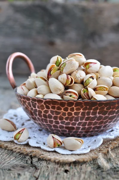 Pistachio  in a copper plate on a wooden table — Stock Photo, Image