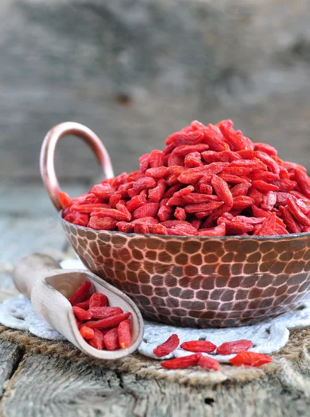 Bacche di goji secche in un piatto di rame su un tavolo di legno — Foto Stock