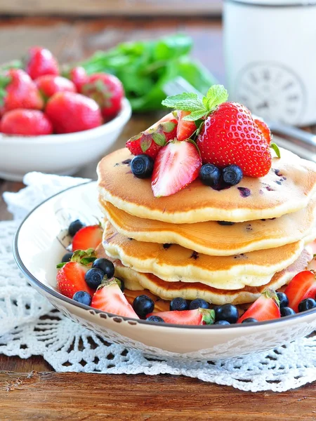Blueberry Pancake dengan stroberi dan secangkir susu di atas meja kayu — Stok Foto