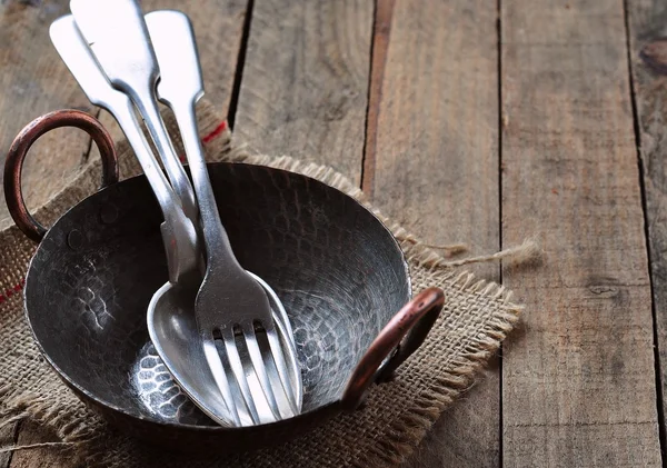 Antieke lepel en vork in een koperen plaat op een houten achtergrond — Stockfoto