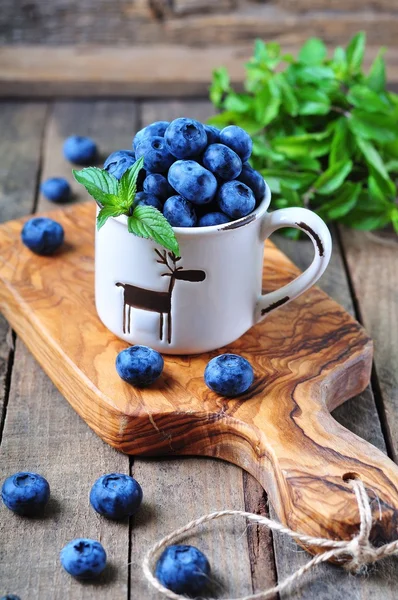 Organic fresh blueberries with peppermint on a wooden background — Stock Photo, Image