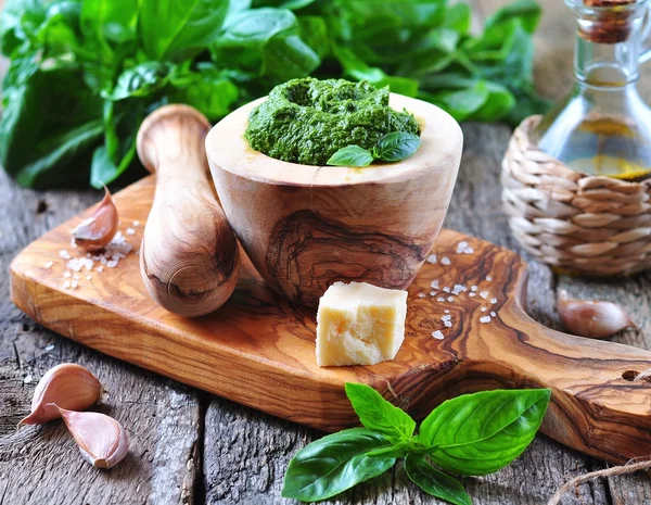 Pesto casero hecho de albahaca orgánica en la tabla de aceitunas con parmesano y ajo — Foto de Stock