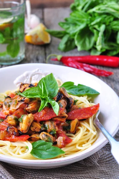 Pasta with mussels, pepperoni, bacon, tomato and basil — Stockfoto