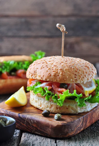 Burger with pickled salmon, lettuce, white onion and capers — Stock Photo, Image