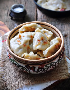 Dumplings with potatoes and mushrooms with fried onions in a traditional ceramic plate on a wooden table. Ukrainian traditional cuisine. rustic style. selective focus