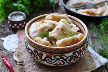 Dumplings with potatoes and mushrooms with fried onions in a traditional ceramic plate on a wooden table. Ukrainian traditional cuisine. rustic style. selective focus