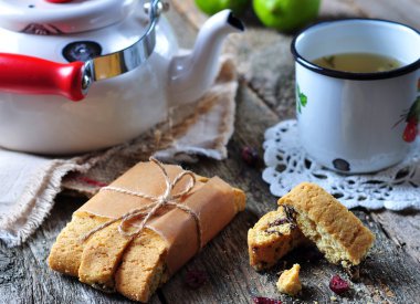 homemade biscotti with dried cranberries and lime, with a cup of green tea kettle on the wooden table. rustic style.