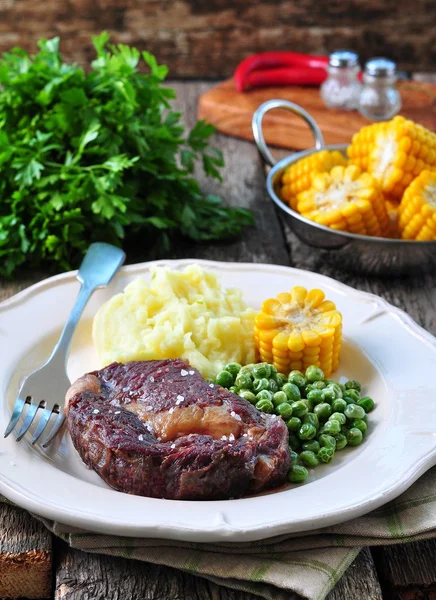 Rare beef steak with mashed potatoes, green peas and boiled corn — Stock Photo, Image