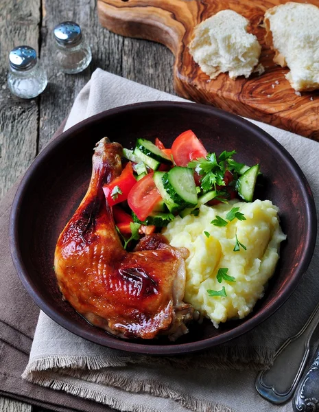 Glazed roasted chicken leg with mashed potatoes and vegetable salad on a wooden background — 스톡 사진