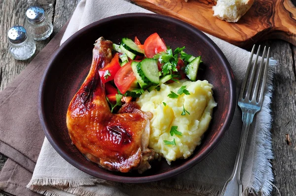 Perna de frango assada com purê de batatas e salada de legumes em um fundo de madeira — Fotografia de Stock