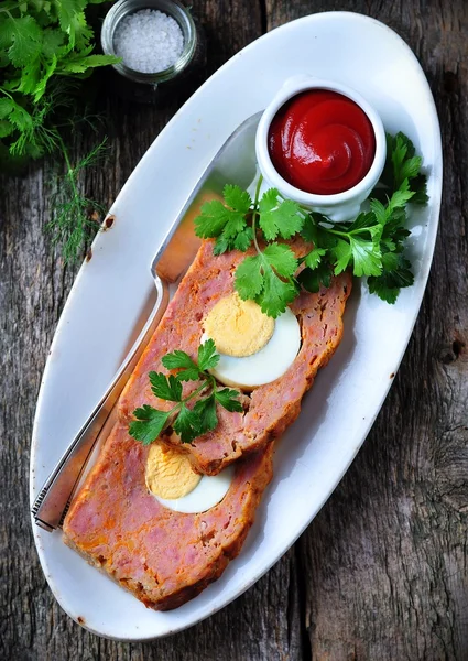 Pastel de carne con huevo cocido, salsa de tomate, cilantro y perejil sobre una mesa de madera. estilo rústico . — Foto de Stock