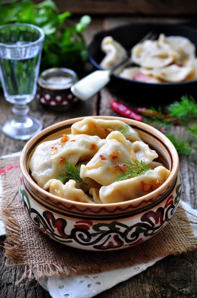 Dumplings with potatoes and mushrooms with fried onions in a traditional ceramic plate on a wooden table. Ukrainian traditional cuisine. rustic style. selective focus — 图库照片