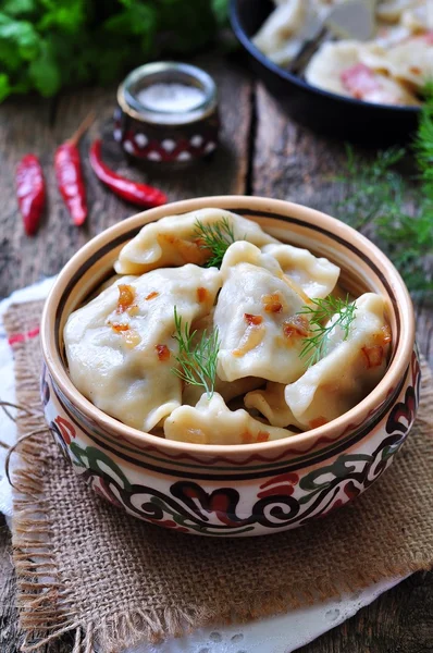 Dumplings with potatoes and mushrooms with fried onions in a traditional ceramic plate on a wooden table. Ukrainian traditional cuisine. rustic style. selective focus — 图库照片