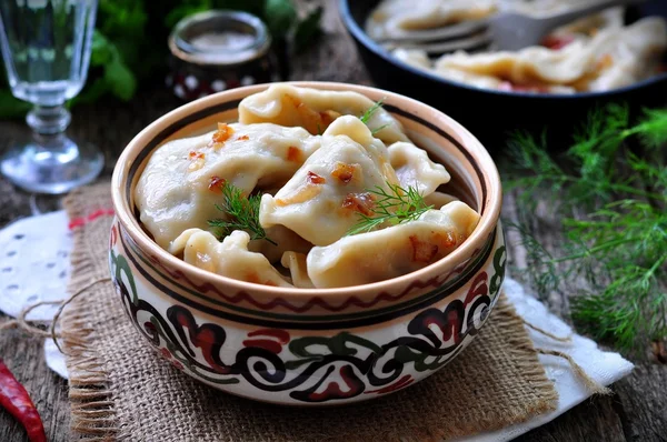 Dumplings with potatoes and mushrooms with fried onions in a traditional ceramic plate on a wooden table. Ukrainian traditional cuisine. rustic style. selective focus — 图库照片