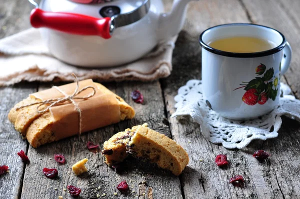 Homemade biscotti with dried cranberries and lime, with a cup of green tea kettle on the wooden table. rustic style. — Stock Photo, Image