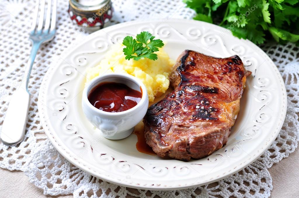 Medium rare grilled Beef steak with mashed potatoes and barbecue sauce