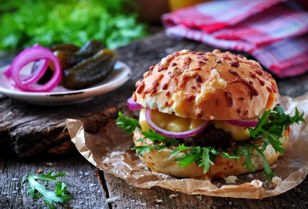 Hamburguesa jugosa con carne de res, queso, lechuga, pepino agrio, cebollas en vinagre y pan de queso — Foto de Stock