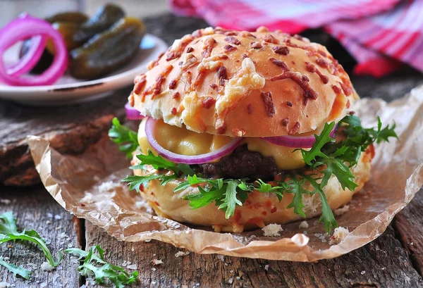 Burger juteux au bœuf, fromage, laitue, concombre aigre, oignons marinés et pain de fromage — Photo