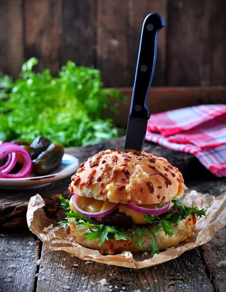 Juicy burger with beef, cheese, lettuce, sour cucumber, pickled onions and cheese loaf — Stock Photo, Image
