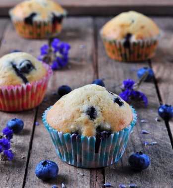 homemade cupcakes with berries and lavender on a wooden table, rustic style