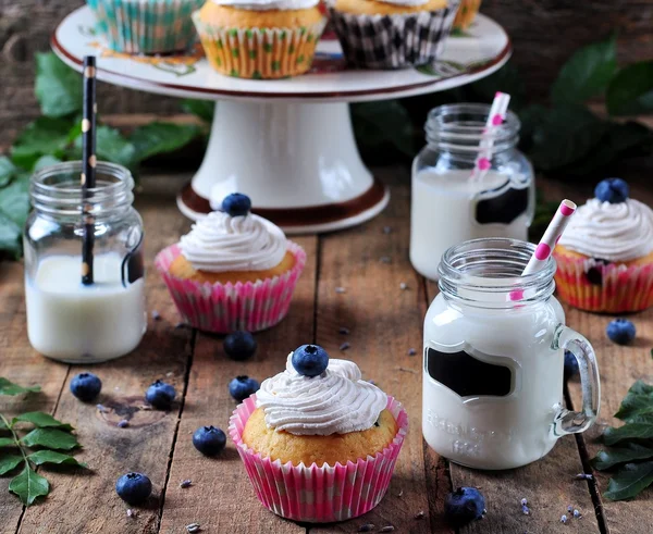 Cupcakes maison aux myrtilles avec un pot de lait sur un fond en bois, style rustique — Photo