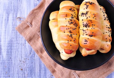 hafif ahşap arka plan üzerinde siyah bir tabak içinde pasta pişmiş sosis