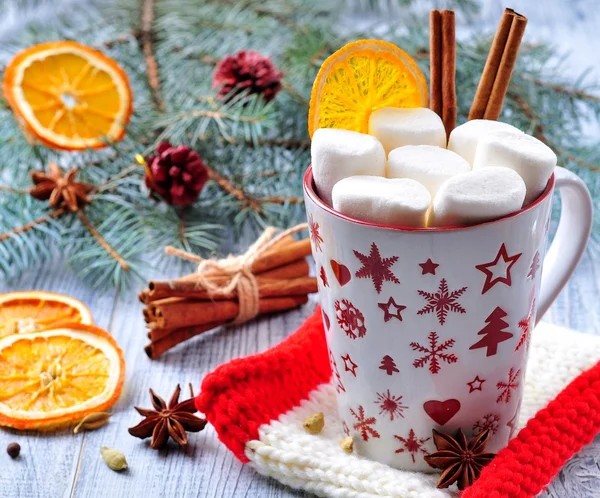 chocolate or cocoa drink with marshmallows and cinnamon in a Christmas cup on the background of blue spruce