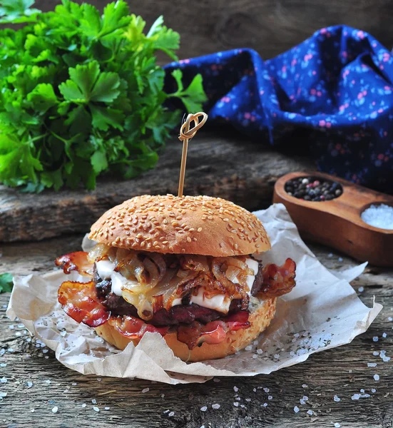 Juicy homemade double burger beef with fried onions on a wooden background — Zdjęcie stockowe