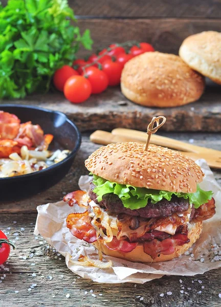 Juicy homemade double burger beef with fried onions on a wooden background — Stock Photo, Image