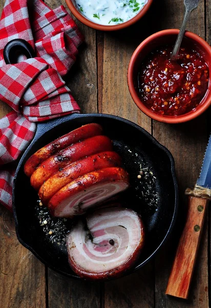 Roast pork belly roll with pepper, sea salt, dried rosemary, basil and garlic on a wooden table. Rustic style. Selective focus. — Stock Image Roast pork belly roll with pepper, sea salt, dried rosemary, basil and garlic on a wooden table. Rustic style. Selective focus. Stock Image