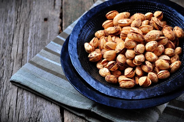 Pistachio flavored barbecue in a black plate on a wooden background — Stock Photo, Image