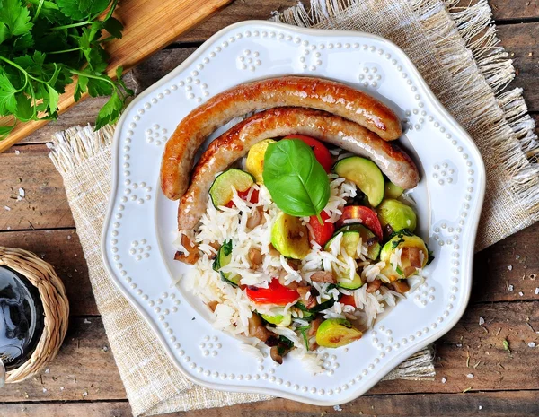 Arroz frito com brotos de Bruxelas, cogumelos, abobrinha, alho, tomate cereja, manjericão, salsa e salsichas de frango — Fotografia de Stock