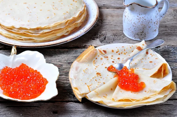 Pancakes with red caviar on a wooden background — Stock Photo, Image