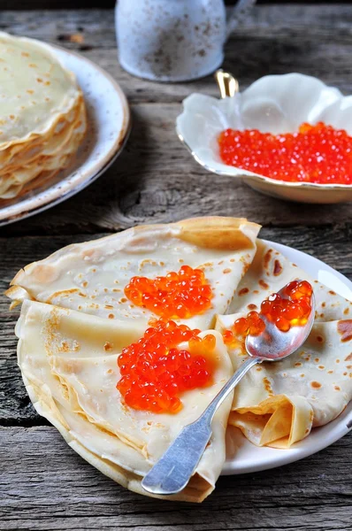 Pancakes with red caviar on a wooden background — Stock Photo, Image