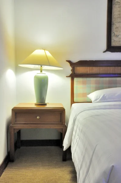 Mesa auxiliar con lámpara y mobiliario en el dormitorio — Foto de Stock