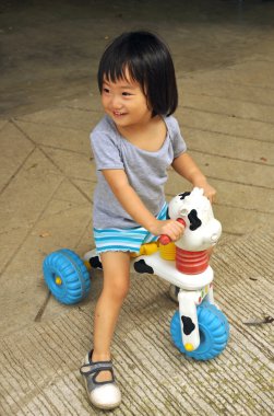 Asian child girl playing on toy with wheels clipart