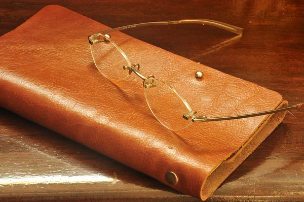 Leather notebook and glasses on wooden background — Stock Photo, Image