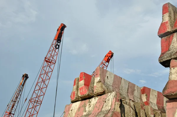 Crane hook and stack of concrete barriers