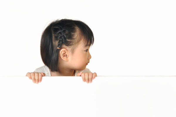 Asian little girl hiding behind white board