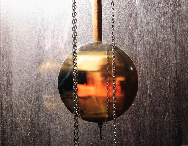 Металлические маятниковые часы, качающиеся на деревянном фоне — стоковое фото